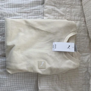 Hoodie från Puma - Säljer en aldrig använd stilren beige sweatshirt från Puma med diskret logga framtill. Tröjan har rund halsringning och långa ärmar, perfekt för en chill och clean look. Tillverkad i mjuk bomull som känns skön mot huden.
