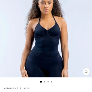 Svart halterneck linne - Säljer ett svart halterneck linne med smala axelband och v-ringning. Toppen är tight och har en croppad passform, perfekt för träning eller en sportig look. Sänker pris vid snabb affär