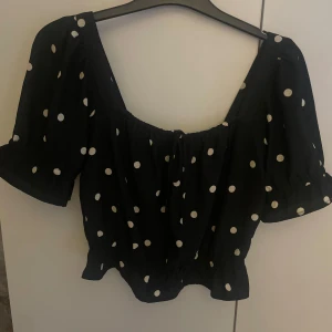 Svart prickig blus från H&M - Supersöt svart blus från H&M med vita prickar och korta puffärmar. 