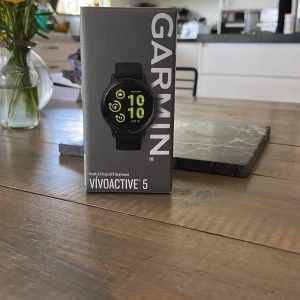 Garmin Vívóactive 5 GPS Smartwatch - Garmin Vívóactive 5 är en stilren svart smartklocka med rund urtavla och digital display. Perfekt för dig som vill ha koll på träning, hälsa och notiser direkt på handleden. Klockan har sportig look och passar dig som gillar teknik och aktivitet. Aldrig använd. Lådan aldrig öppnad. Butikspris 3500. 