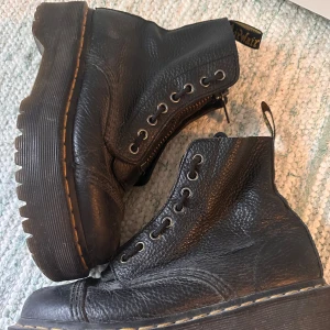 Dr. martens modell Sinclair - Svarta boots från Dr. Martens i grovt skinn med snörning och dragkedja framtill. Med tjock sula, väldigt bekväma när man gått in dom! Nypris 2500, priset kan diskuteras