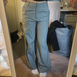 Grå rutiga kostymbyxor - Snygga grå kostymbyxor från Cubus i storlek 40. Byxorna är rutiga med hög midja och vida ben. 