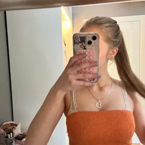 Orange ribbad tubtopp med spetsdetalj - Säljer en orange topp. Toppen är croppad och har en tight passform som framhäver figuren. Perfekt för varma dagar och ger en trendig vibe till din outfit.