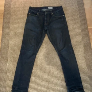 Mörkblå skinny jeans från Tiger of Sweden - Ett par väldigt snygga mörkblå skinny jeans från Tiger of Sweden med klassisk femficksdesign och beiga kontrastsömmar. Jeansen har en smal passform och är tillverkade i stretchigt denim för extra komfort. De är de perfekta skinny jeansen och är väldigt snygga året om. Styl: pistolero och storlek: 31x30