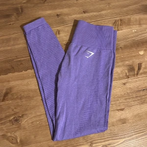 Lila seamless leggings från Gymshark - Säljer ett par lila seamless leggings från Gymshark i storlek S. De har hög midja, ribbad linning och diskret prickigt mönster längs benen. Perfekta för träning och riktigt sköna tack vare stretchigt syntetmaterial.