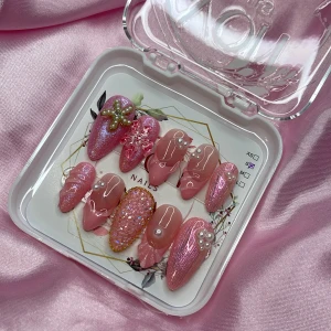 CandyShell (S);Medium Almond - Gelé-press-on naglar i olika rosa nyanser. Naglarna har detaljer som pärlor, 3D-blommor, glitter, metallic-effekt och guldkanter. Perfekt för dig som vill ha unika och glamorösa naglar med extra bling och dekorationer. I storlek S: 15 mm, 11,5 mm, 12 mm, 11 mm, 9 mm 