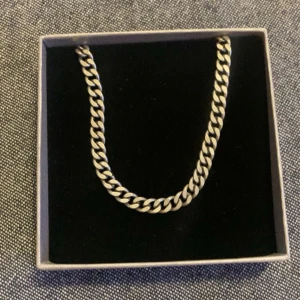 Kedjehalsband i silverfärg - Säljer ett stilrent halsband med platt pansarlänk gjord på äkta silver från guldfynd. Halsbandet har en klassisk karbinhake och passar perfekt för dig som gillar en clean och tidlös look.  Halsbandet är 45 cm långt och har en bredd på 5 mm. 