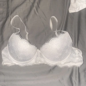 Vit spets-bh från H&M 75A - Säljer en vit bh från H&M i storlek 75A med fina spetsdetaljer och vadderade kupor. Bh:n har justerbara axelband och dekorativ kant i spets. Materialet är mjukt och stretchigt för extra komfort.