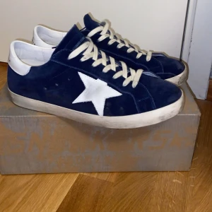 Blå Golden Goose - Snygga sneakers från Golden Goose i mörkblå mocka med vit stjärndetalj på sidan och vit hälkappa. Klassisk platt sula och vita snören. Skorna är endast använda 2 gånger och mycket varsamt med absolut inga täcken på användning så gott som nya 