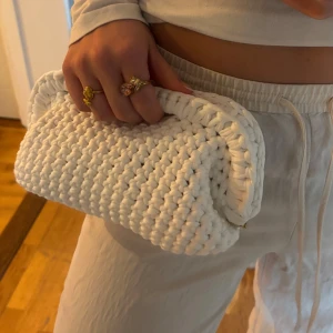 Vit handvirkad clutch  - Säljer en vit handvirkad clutch / handväska som jag har virkat! Väskan är i ett mjukt garn och är väldigt rymlig! Kan bäras i handen som en clutch eller bäras i handtaget.
