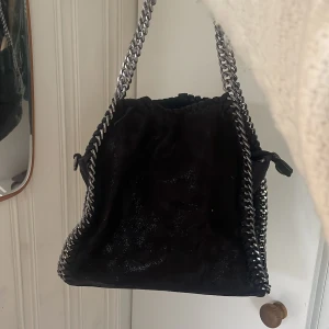 Svart axelväska med kedjedetaljer - Snygg Stella Mcartney-liknande väska. Vet inte vad det är för märke eller originalpris för den är vintage, säljer endast för att jag alltid bär guld då den inte matchar 🥰