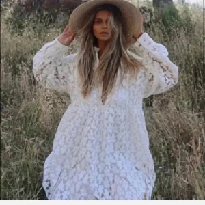 Vit spetsklänning från Zara - Superfin vit kortklänning från Zara med blommigt spetsmönster och långa ärmar. Klänningen har snörning vid halsen och en luftig passform. Perfekt för sommarens alla tillfällen och ger en romantisk vibe.