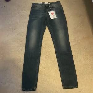 Acne Studios skinny jeans blå 26/34 - Snygga blå skinny jeans från Acne Studios med klassisk femficksdesign och dragkedjegylf. Jeansen har en lätt tvättad look och smal passform som sitter tajt längs benen. Tillverkade i bomull med en touch av stretch för extra komfort.