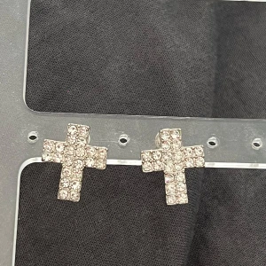 Glittriga korsformade örhängen - Snygga örhängen i form av kors, täckta med glittrande stenar som ger en riktigt cool och trendig vibe. Perfekta för att lyfta vilken outfit som helst med extra bling. Fästs med klassisk plupp på baksidan.