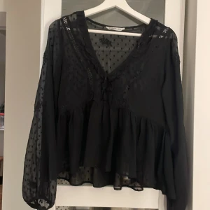 TRYCK EJ PÅ KÖP! Skriv och köp varan hos Alicen!  - Supersöt svart blus från Stradivarius med transparenta ärmar och prickigt mönster. V-ringad med spetsdetaljer och volang nedtill. Lätt och luftig känsla, perfekt att styla med jeans eller kjol.