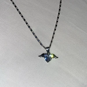 Halsband med hjärta och vingar - Snyggt halsband i silverfärg med en kedja och ett glittrande hängsmycke format som ett hjärta med små vingar på sidorna. Helt nytt!💕