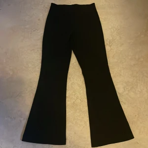 Svarta bootcut byxor från Zara - Snygga svarta bootcut byxor från Zara med hög midja och utsvängda ben. Byxorna är i ett stretchigt material som sitter skönt och ger en clean siluett. Perfekta för dig som gillar en stilren look med lite edge.