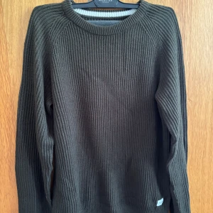 Mörkgrön ribbstickad tröja från Jack and Jones  - Säljer en mörkgrön ribbstickad tröja från Jack and Jones. Tröjan har rund halsringning och långa ärmar, perfekt för lager-på-lager under höst och vinter. Enkel och stilren design som funkar till det mesta.