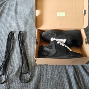 Etnies Fader  - Svarta Etnies sneakers med breda vita skosnören. Svarta skosnören ingår. Skorna har en klassisk låg profil, rund tå och platt sula. Materialet är en mix av mocka och syntet. Bara använda 3 gånger                                                                                Nypris: 999kr. 