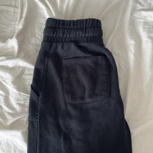 Svarta mjukisbyxor med snörning - Svarta mjukisbyxor med bred resår i midjan och snörning framtill. Byxorna har stora fickor både fram och bak samt raka ben. Perfekta för chill dagar eller när du vill vara bekväm men ändå se stilren ut. 