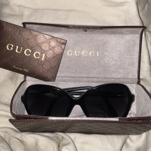 Svarta solglasögon från Gucci - Snygga svarta solglasögon från Gucci med stora, fyrkantiga bågar och mörka glas. Kommer med originalfodral i brunt med GG-mönster och guldtext. Riktigt lyxig vibe och perfekt accessoar för att lyfta din stil. Pris går att diskutera 