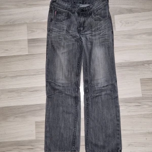 Grå jeans från Beavers, raka ben - Säljer ett par grå jeans från Beavers i storlek 146. Jeansen har raka ben, klassisk femficksdesign och snygga slitningar framtill. Materialet är jeans och färgen är en tvättad grå nyans med ljusare partier. Perfekta för en avslappnad och cool stil. Har några slitage,  se bilderna. 