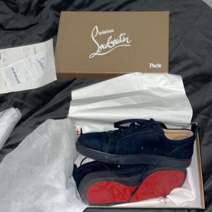 Mörkblå sneakers från Louboutin - Snygga mörkblå sneakers från Christian Louboutin i lyxig mocka med klassisk röd sula. Skorna har rund tå, svarta snören och diskreta nitar på sidan. Perfekta för dig som vill sticka ut.       Box ingår!📦 