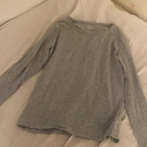 Grå långärmad tröja från Cubus - En basic grå långärmad tröja från Cubus i mjuk bomull. Enkel och stilren med rund halsringning och normal passform. Perfekt att matcha med jeans eller under en hoodie för en chill look.