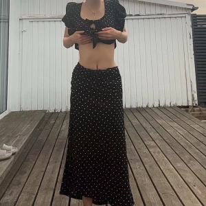 Svart långkjol med vita prickar - Super fin svart långkjol. Har en slits på sidan. Matchande tröja finns också uppe
