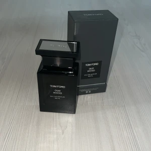 Tom Ford Oud Wood 100 ml parfym - Tom Ford Oud Wood Eau de Parfum i en elegant svart, fyrkantig flaska på 100 ml. Parfymen har en lyxig och stilren design med tydlig logotyp på framsidan. Kommer med originalkartong i matchande svart färg. Perfekt för dig som gillar exklusiva dofter.