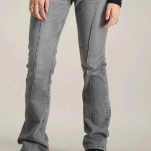 Grå bootcut jeans från Gina Tricot - Snygga grå jeans från Gina Tricot i bootcut-modell. Byxorna har markerade sömmar framtill och raka bakfickor. Jeansen är i klassisk denim med en cool, lite tvättad look och passar perfekt till sneakers eller boots.