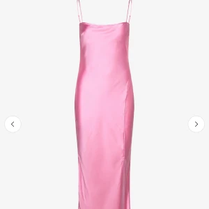 Rosa långklänning i satin med smala band - Supersnygg rosa långklänning i satin med smala axelband och rak siluett. Klänningen har en minimalistisk look och glansigt material som ger en lyxig känsla. Perfekt för dig som vill sticka ut med en enkel men elegant stil.