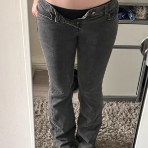 Mörkgrå bootcut jeans - Säljer ett par mörkgrå jeans med bootcut passform. Jeansen har klassisk femficksdesign, låg midja och är tillverkade i mjukt denimtyg. Perfekta för dig som gillar en avslappnad men ändå snygg design. Lappen är avklippt och de är köpa här på plick så jag vet ej vart de är ifrån