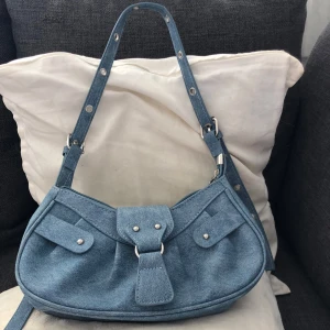 Blå jeans axelväska - Snygg axelväska i ljusblått jeanstyg med justerbart axelband, och silvriga detaljer.