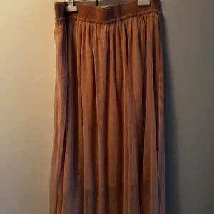 Rosa långkjol från H&M i storlek L - Lång, plisserad beige kjol från H&M i storlek L. Kjolen har bred resår i midjan för extra komfort och ett snyggt fall. Katt finns i hemmet, kontakta vid fler frågor🌷