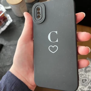 Svart mobilväska med hjärta och bokstaven C - Snygg svart mobilväska med ett stilrent tryck av bokstaven C och ett hjärta under. . Perfekt accessoar för att skydda din mobil och ge den en personlig touch. Helt oanvänt fick av en kompis