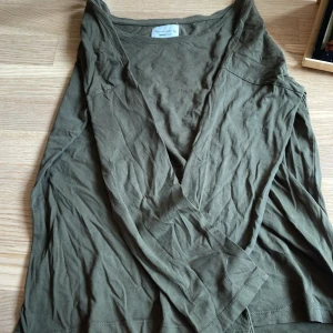 Olivgrön långärmad tröja från Gina Tricot - Säljer en olivgrön långärmad tröja från Gina Tricot i ekologisk bomull. Tröjan har v-ringning och är enkel i modellen, perfekt för en avslappnad stil. Passar dig som gillar basic och bekväma plagg.