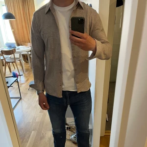 Beige skjorta från J.Lindeberg - Skön skjorta som är använd 2 gånger, då jag tycker att den är aningen tight på mig. Inga defekter och fin i färgen. 