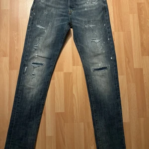 Blå slitna jeans - Snygga blå jeans med slitningar och en cool, distressed look. Perfekta för en avslappnad stil. Midjemått är 29 och längden 30. Passar bra för dig som gillar en trendig och bekväm stil. Använda 1 gång.