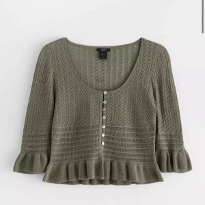 Olivgrön stickad kofta med volang från Lindex - Köpt för 400 kr🥰🥰Supersöt olivgrön stickad kofta från Lindex med dekorativa knappar framtill och volangdetalj vid ärmslut och nederkant. Koftan har trekvartsärm och ett fint mönster i stickningen. Perfekt att styla till både jeans och kjol.