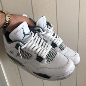 Nike Air Jordans 4 Retro vit/grön - Säljer ett par Nike Air Jordans 4 Retro i vitt med gröna detaljer. Skorna har klassisk mesh vid tårna och sidorna, samt snörning och platt sula.  PRIS KAN DISKUTERAS