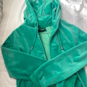 Grön velour hoodie från Juicy Couture - Juicy Couture hoodie i grön velour med dragkedja och huva. Bra skick, vill bara bli av med massa kläder som jag inte använder så säljer den för 230kr. Storlek L men passar som M/S. Färgen är grönare i verkligheten.