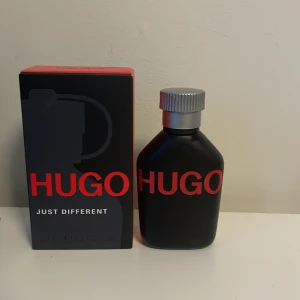 Hugo Just Different Eau de Toilette 40 ml - En stilren och modern parfym från Hugo Boss, Just Different. Flaskan är matt svart med röd text och har en silverfärgad kork. Doften har noter av mynta, basilika, fresia och cashmeran. Perfekt för dig som vill sticka ut med en fräsch och unik doft. Har andvänt max 15 sprut och den är jätte fräsch men fick en till i födelsedagspresent! 