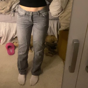 Grå jeansbyxor med normal passform - Säljer ett par grå jeansbyxor med klassisk femficksdesign och normal passform. Byxorna har raka ben och stängs med dragkedja och knapp. Perfekta till vardags för en avslappnad stil.