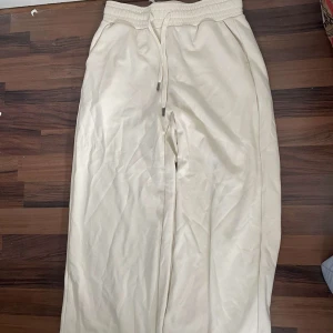 Beige mjukisbyxor från SoyaConcept - Säljer ett par beige mjukisbyxor från SoyaConcept med resår och dragsko i midjan. Byxorna har en loose passform och är perfekta för en avslappnad stil. Mjukt material som känns skönt mot huden.