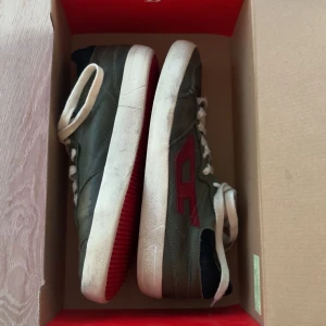 Mörkgröna diesel sneakers  - Säljer ett par gröna Diadora sneakers med vit sula och röd logga på sidan. Skorna har vita snören och svarta detaljer vid hälen. Perfekta för dig som gillar klassisk streetstil.