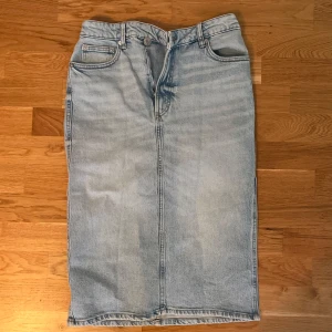 Ljusblå jeanskjol från Zara - Säljer en ljusblå jeanskjol från Zara i klassisk femficksmodell. Kjolen är rak och har normal passform med knapp och dragkedja framtill. Tillverkad i bomull med lite stretch för extra komfort. 