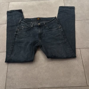 Mörkblå jeans från Lee - Säljer ett par klassiska mörkblå jeans från Lee med fem fickor och raka ben. Jeansen har normal passform och är tillverkade i bomull. Perfekta för dig som gillar en tidlös stil och vill ha ett par jeans som funkar till det mesta.