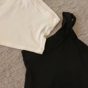 Svart och vit oneshoulder topp - Två stilrena oneshoulder toppar i svart och vitt. Perfekta att matcha till olika outfits och enkla att styla. Mjukt material och trendig asymmetrisk design. Passar mig som är strl XS