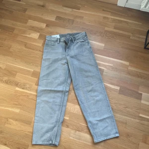 Grå loose fit jeans från H&M - Säljer ett par gråa loose fit jeans från H&M. Byxorna har klassisk femficksdesign, raka ben och normal midja. Perfekta för en avslappnad stil och passar till det mesta. Dragkedja och knapp i gylfen.